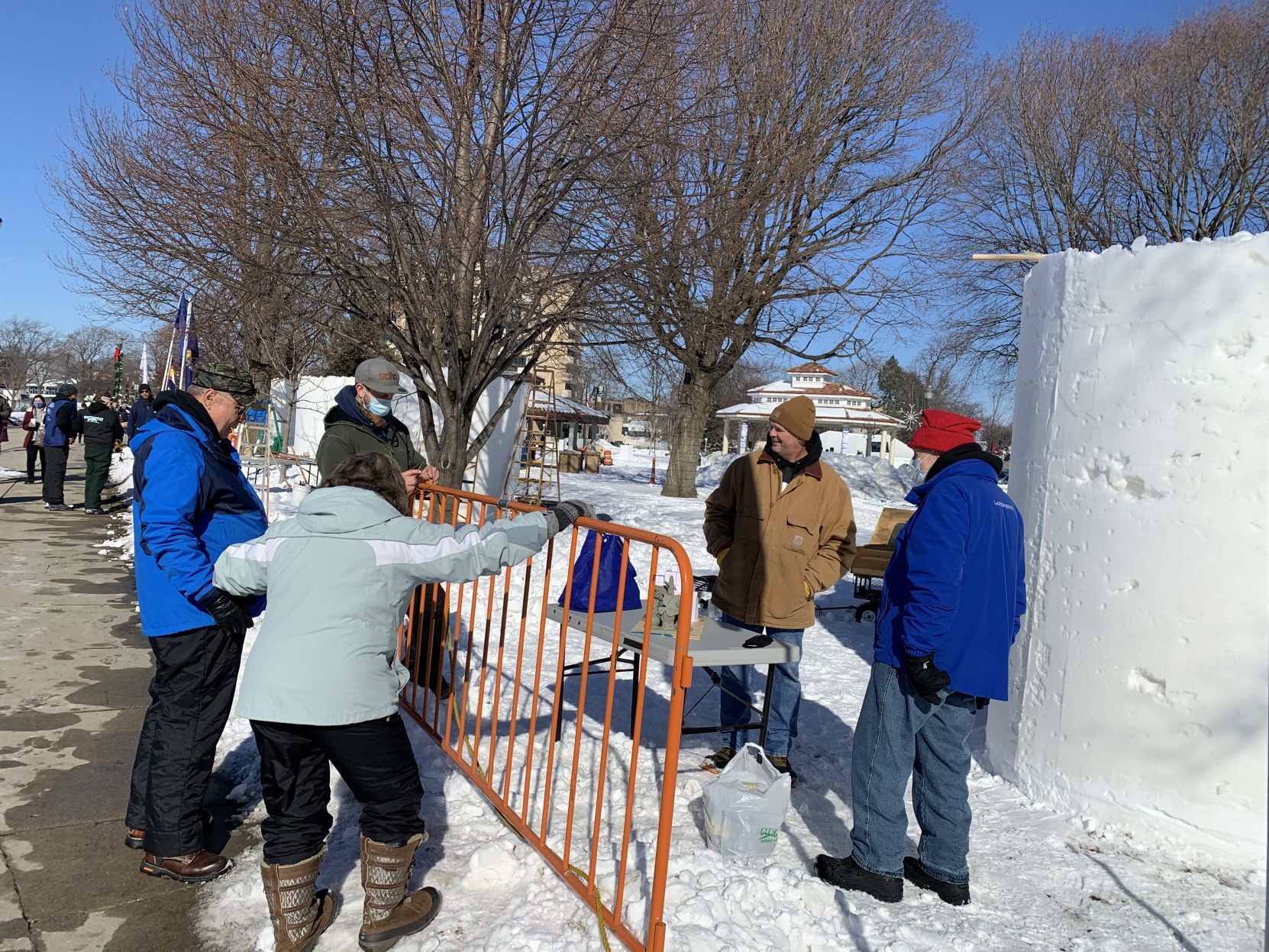 A snow sculpting team greets a group of spectators at Flat Iron Park, as they begin to work on their snow sculpture